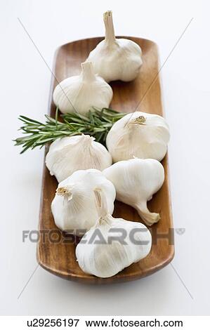 Stock Photo - Studio shot of fresh garlic and rosemary on wooden plate. Fotosearch