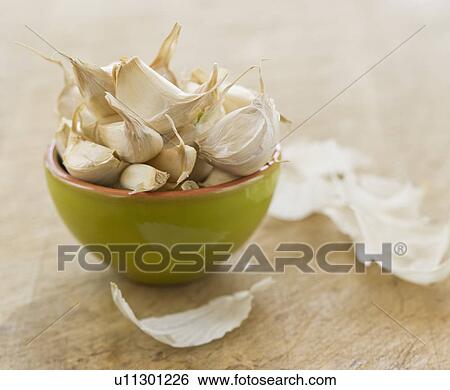 Stock Photograph - Studio shot of fresh garlic cloves in green bowl. Fotosearch