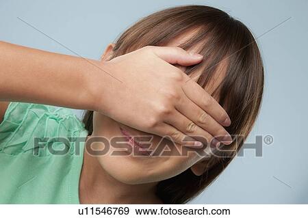 Stock Photo - Studio shot of girl (10-11) covering eyes with hand. Fotosearch