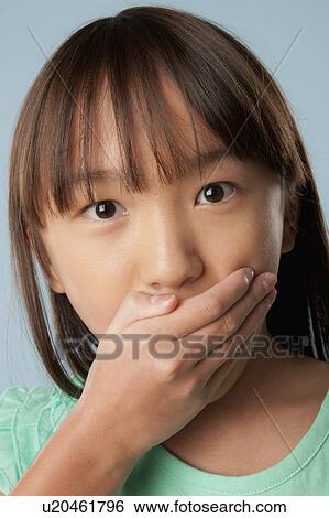Studio shot of girl (10-11) covering mouth with hand View Large Photo Image Stock Photograph - Studio shot of girl (10-11) covering mouth with hand. Fotosearch