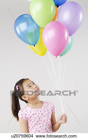 Studio shot of girl (8-9) holding bunch of balloons View Large Photo Image Picture - Studio shot of girl (8-9) holding bunch of balloons. Fotosearch