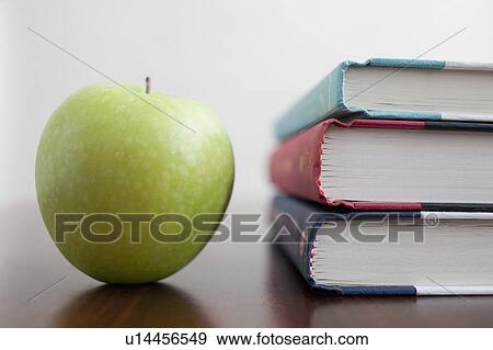 Stock Photo - Studio shot of green apple and textbooks. Fotosearch