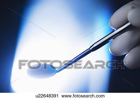 Stock Image - Studio shot of hand holding angled mirror. Fotosearch