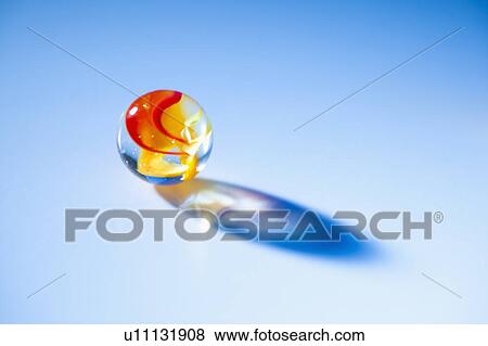 Stock Photo - Studio shot of marble ball on blue background. Fotosearch