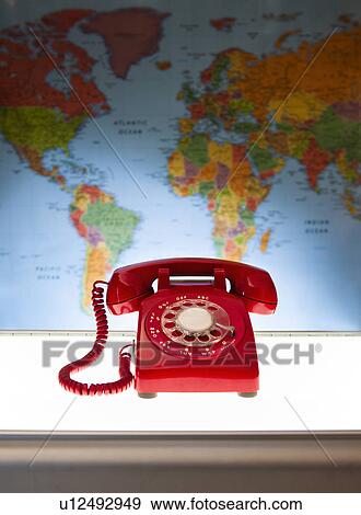 Stock Photo - Studio shot of red phone in front of world map. Fotosearch
