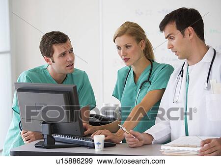 Stock Photo - Team of doctors looking at computer. Fotosearch