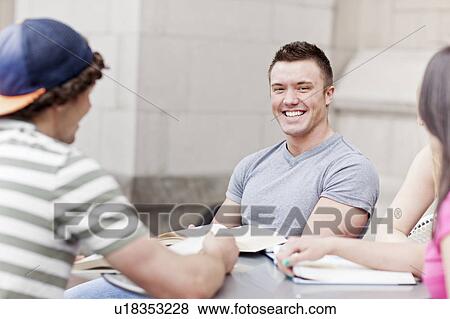 Stock Photo - Three college students sitting at cafe table. Fotosearch