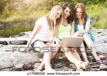 Three young women hanging out on beach, using laptop View Large Photo Image Stock Photo - Three young women hanging out on beach, using laptop. Fotosearch