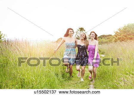 Three young women running in meadow View Large Photo Image Stock Photo - Three young women running in meadow. Fotosearch