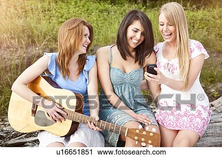 Three young women with guitar and cell phone relaxing View Large Photo Image Stock Image - Three young women with guitar and cell phone relaxing. Fotosearch