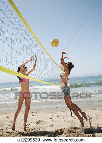 Stock Photo - Two attractive young women playing beach volleyball . Fotosearch