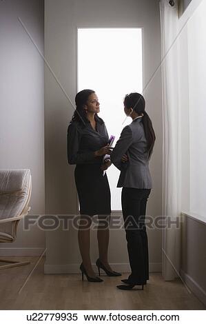 Stock Photography - Two business women discussing in office. Fotosearch
