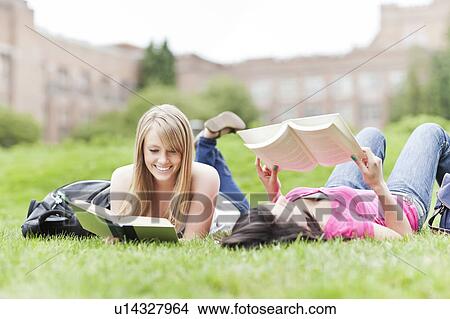 Two female college student lying on grass reading books View Large Photo Image Picture - Two female college student lying on grass reading books. Fotosearch