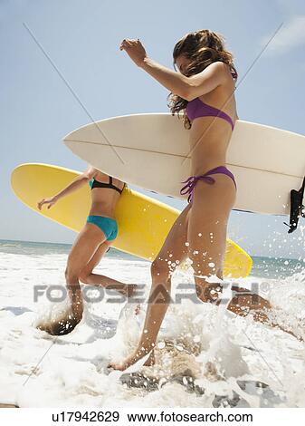 Two young attractive women running into water with swimming boards View Large Photo Image Stock Photo - Two young attractive women running into water with swimming boards. Fotosearch