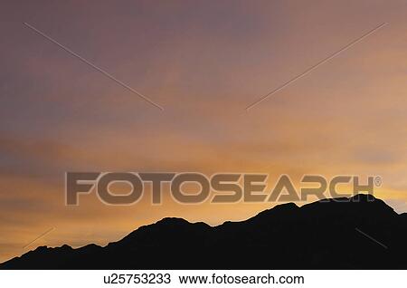Stock Image - USA, California, Silhouette of ridge at sunset. Fotosearch