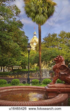 Stock Photograph - USA, Georgia, Savannah, Fountain in park with dome of City Hall in background. Fotosearch