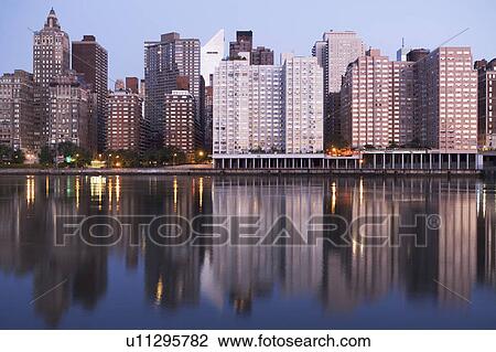 Stock Image - USA, New York State, New York City, Manhattan, Skyscrapers of Manhattan at dusk. Fotosearch