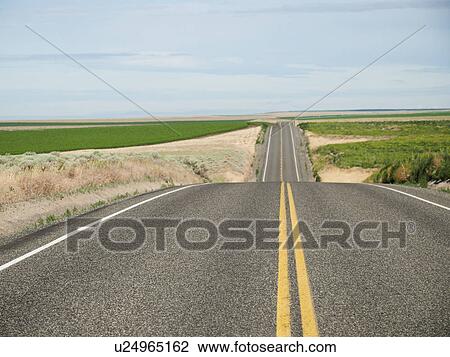 Stock Image - USA, Oregon, Boardman, Rolling landscape with empty road. Fotosearch