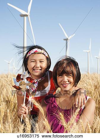 Stock Photography - USA, Oregon, Wasco, Portrait of two girls (10-11, 12-13) standing in wheat field, wind turbines in background. Fotosearch