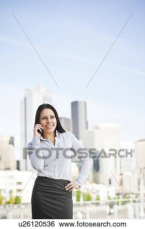 USA, Washington, Seattle, Young businesswoman talking on phone with city skyline behind View Large Photo Image Stock Photograph - USA, Washington, Seattle, Young businesswoman talking on phone with city skyline behind. Fotosearch