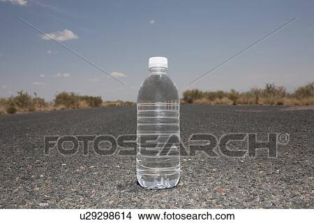 Picture - Water bottle sitting in middle of desert road. Fotosearch
