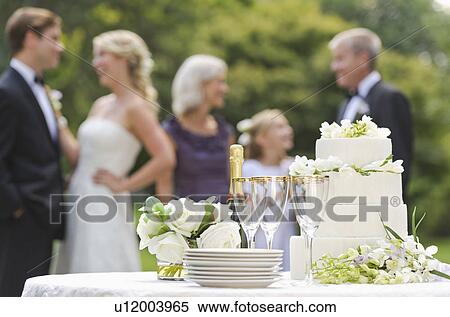 Stock Photography - Wedding table with champagne and cake, people in background. Fotosearch