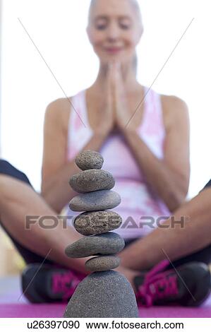 Woman doing yoga behind stack of pebbles View Large Photo Image Stock Image - Woman doing yoga behind stack of pebbles. Fotosearch