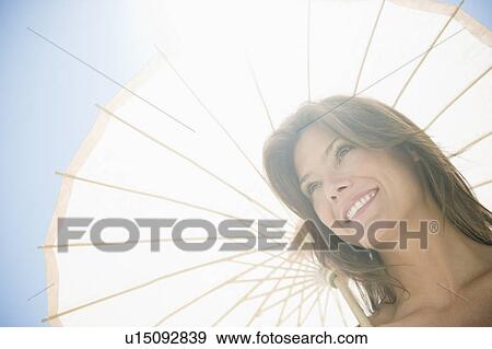 Stock Photo - Woman in sunlight with parasol. Fotosearch