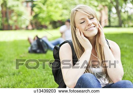 Stock Image - Woman listening to mp3 player in park. Fotosearch