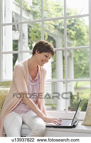 Woman using laptop at home View Large Photo Image Stock Image - Woman using laptop at home. Fotosearch