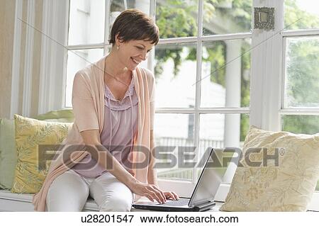 Woman using laptop at home View Large Photo Image Stock Photo - Woman using laptop at home. Fotosearch
