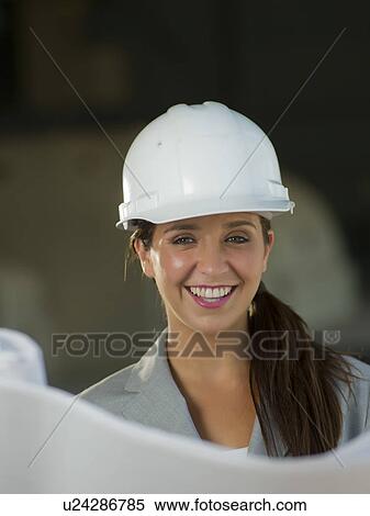 Woman wearing hardhat reading blueprint View Large Photo Image Stock Photography - Woman wearing hardhat reading blueprint. Fotosearch