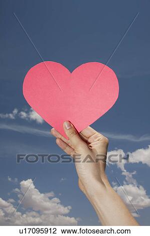Woman's hand holding pink heart shape against sky View Large Photo Image Stock Image - Woman's hand holding pink heart shape against sky. Fotosearch