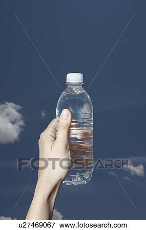 Woman's hand holding water bottle against sky View Large Photo Image Stock Photo - Woman's hand holding water bottle against sky. Fotosearch