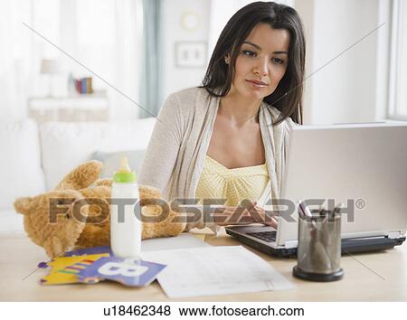 Stock Photo - Working mother using laptop at home. Fotosearch