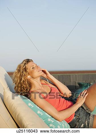 Stock Image - Young attractive listening to music on terrace. Fotosearch