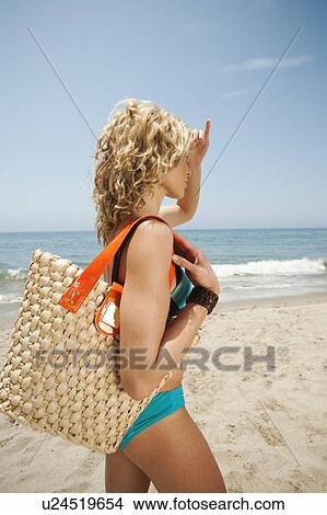 Young attractive woman carrying straw bag on sandy beach View Large Photo Image Picture - Young attractive woman carrying straw bag on sandy beach. Fotosearch