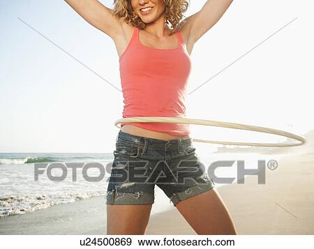 Stock Photo - Young attractive woman exercising with hoola hoop. Fotosearch