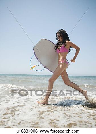 Young attractive woman running into water with swimming boards View Large Photo Image Stock Photograph - Young attractive woman running into water with swimming boards. Fotosearch