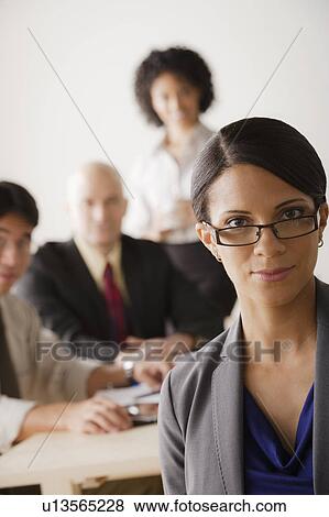 Young businesswoman looking at camera, business team in background View Large Photo Image Stock Photo - Young businesswoman looking at camera, business team in background. Fotosearch