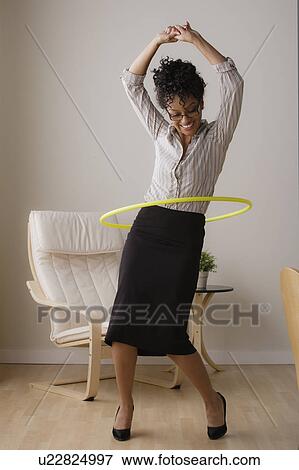 Stock Photo - Young businesswoman using hoola hoop. Fotosearch