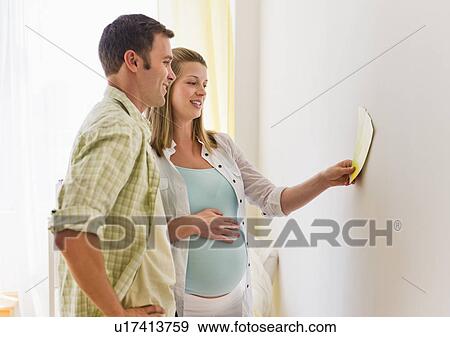 Young couple choosing wall color for nursery View Large Photo Image Stock Photo - Young couple choosing wall color for nursery. Fotosearch