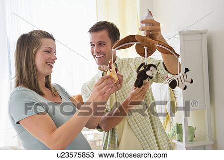 Young couple holding mobile in nursery View Large Photo Image Stock Image - Young couple holding mobile in nursery. Fotosearch
