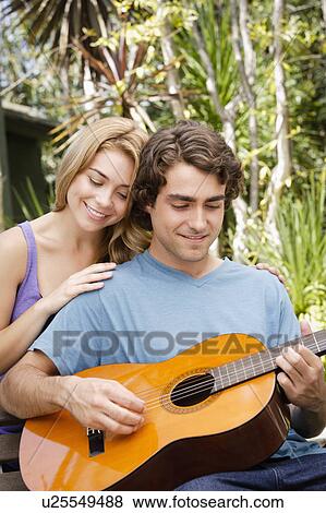 Young couple in park, man playing guitar View Large Photo Image Stock Photo - Young couple in park, man playing guitar. Fotosearch
