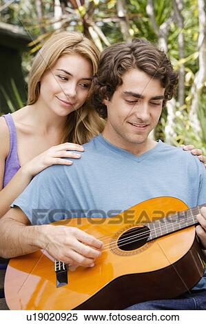 Young couple in park, man playing guitar View Large Photo Image Stock Photography - Young couple in park, man playing guitar. Fotosearch