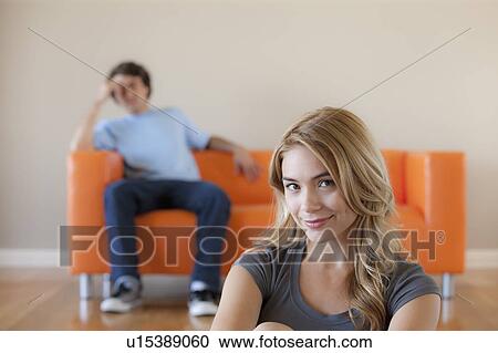 Young couple in room, focus on woman in foreground View Large Photo Image Stock Image - Young couple in room, focus on woman in foreground. Fotosearch