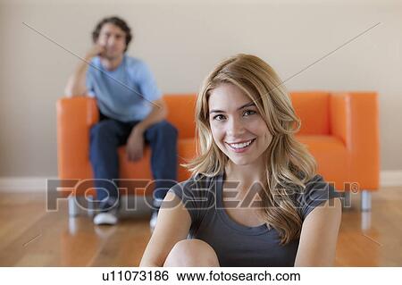 Stock Photograph - Young couple in room, focus on woman in foreground. Fotosearch
