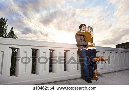 Picture - Young couple kissing on bridge. Fotosearch
