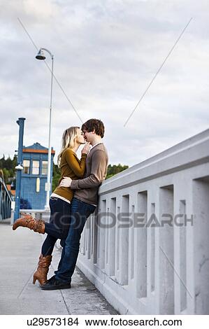 Picture - Young couple kissing on bridge. Fotosearch