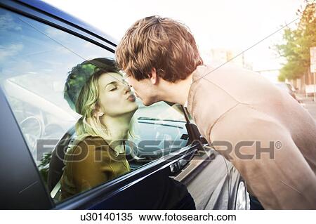 Stock Photography - Young couple kissing through window of car. Fotosearch